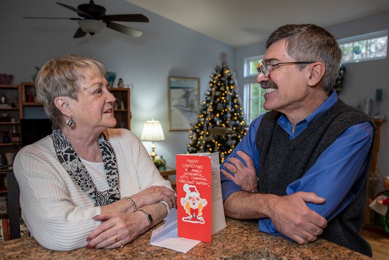 Jeanne Smith, left, and Mike DeNardo, right, with the Christmas card they have been mailing back and forth to each other for the last 35 years, at Smith’s Pemberton, NJ home on December 10, 2019.