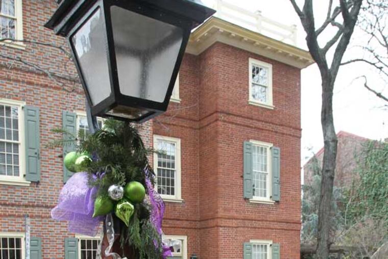 The 200 blocks of Spruce and Delancey Sts. have decorated their Franklin-style street lights with various themes. Resident Laura Temple makes some adjustments to the street light she decorated on Delancey St. with a New Orleans theme. ( Charles Fox / Staff Photographer )