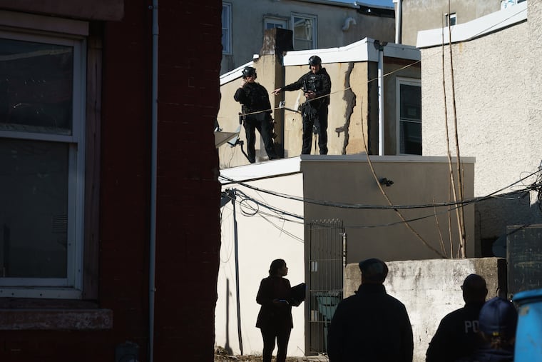 Police investigate North Palethorp Street, near the scene where a SWAT officer was shot Friday.