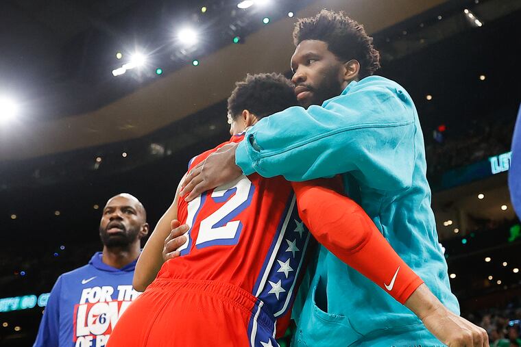 Injured Sixers center Joel Embiid hugs forward Tobias Harris before the start of Game 1 of the Eastern Conference semifinals in Boston on Monday.