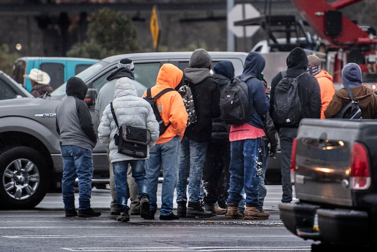 Unidentified man line up to find labor work outside a Home Depot parking lot in Philadelphia, Pa. Wednesday, December 29, 2021. Every day more than 100 men wait in the parking lot of the Home Depot looking for work. Drivers of vans and trucks pass by slowly, laden with building supplies from the nearby Home Depot. They eye the scrum of laborers to see if they can make a match.