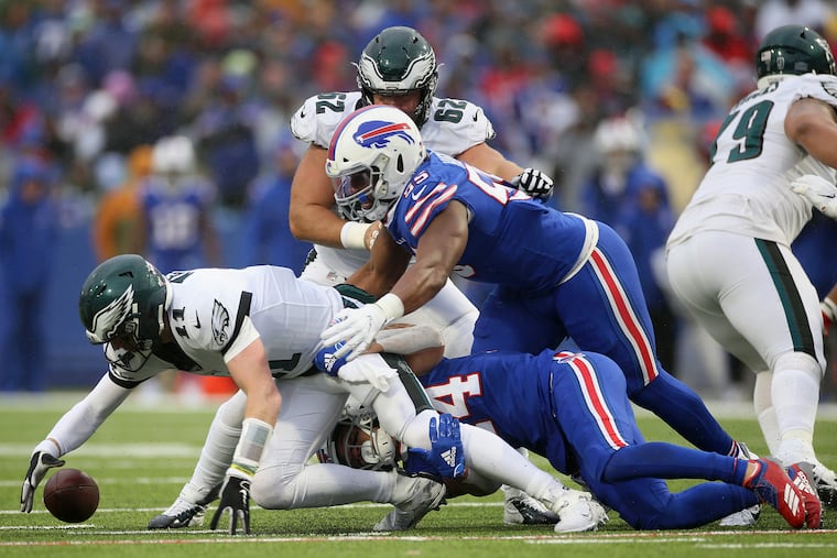 Eagles quarterback Carson Wentz recovers his own fumble while pressured by Buffalo defenders..