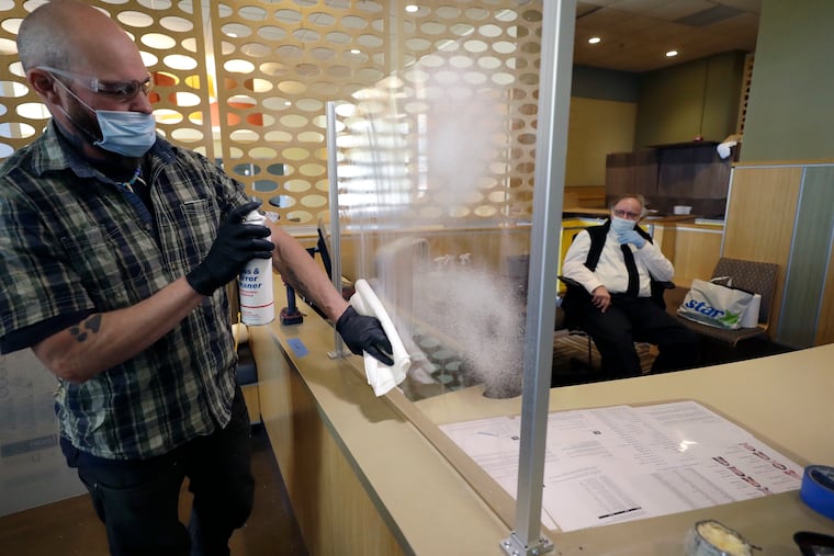 A glass installer cleans a newly installed plastic barrier Thursday, May 21, 2020, at a dormitory entrance at Boston University. BU is among a growing number of universities making plans to bring students back to campus this fall, with new measures to combat the coronavirus.