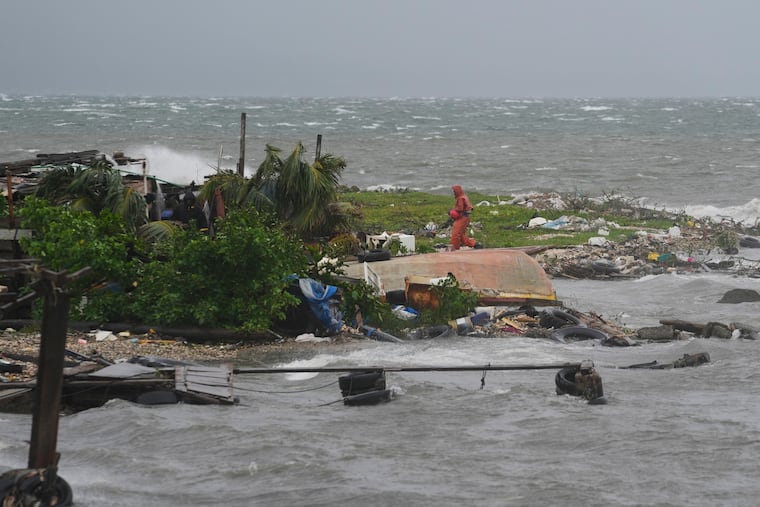A man walks along the coastline in Kingston, Jamaica, as Hurricane Melissa approaches on Tuesday, Oct. 28.