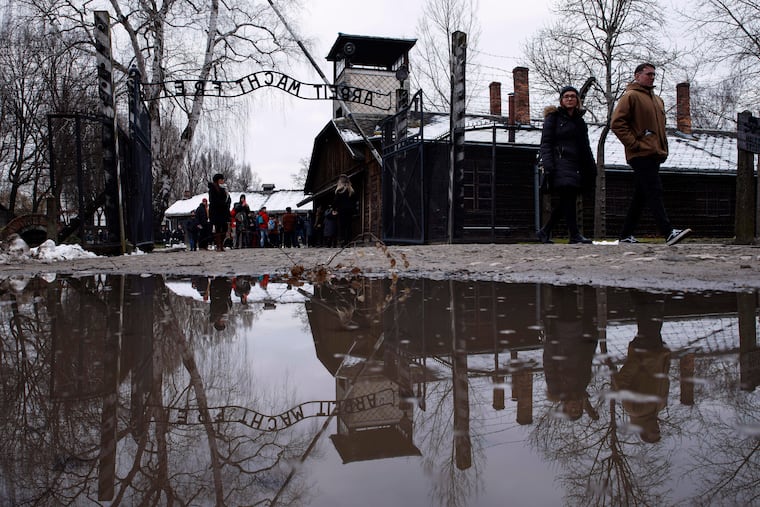 People walk next to the ''Arbeit Macht Frei" (Work Sets You Free) gate at the former Nazi German concentration and extermination camp Auschwitz-Birkenau in Oswiecim, Poland, Thursday, Jan. 26, 2023. Survivors of Auschwitz-Birkenau are gathering to commemorate the 78th anniversary of the liberation of the Nazi German death camp in the final months of World War II, amid horror that yet another war has shattered the peace in Europe. The camp was liberated by Soviet troops on Jan. 27, 1945.
