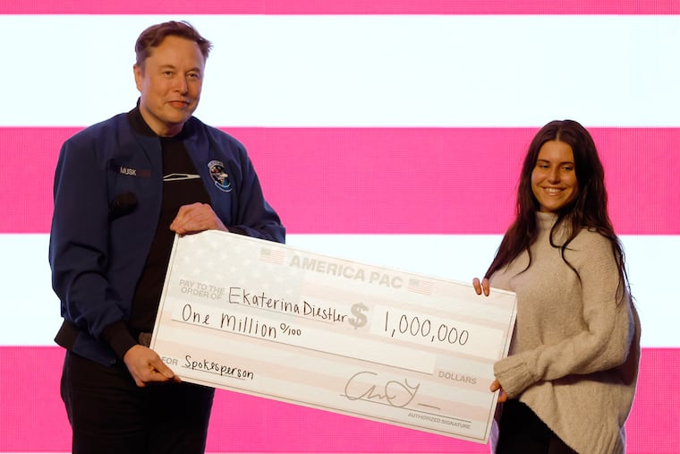 Elon Musk presents a voter with a check for $1 million during a town hall Sunday in Green Bay, Wis.