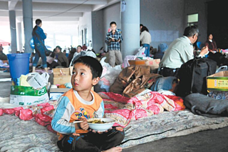 A boy eats a meal delivered by Christian volunteers at the Jiuzhou sports gymnasium, the main center for help for displaced families. (Jennifer Lin / Inquirer)