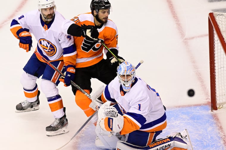 A shot goes over the net as Islanders goaltender Thomas Greiss, Islanders defenseman Andy Greene (left), and Flyers center Scott Laughton looks on in the second period.