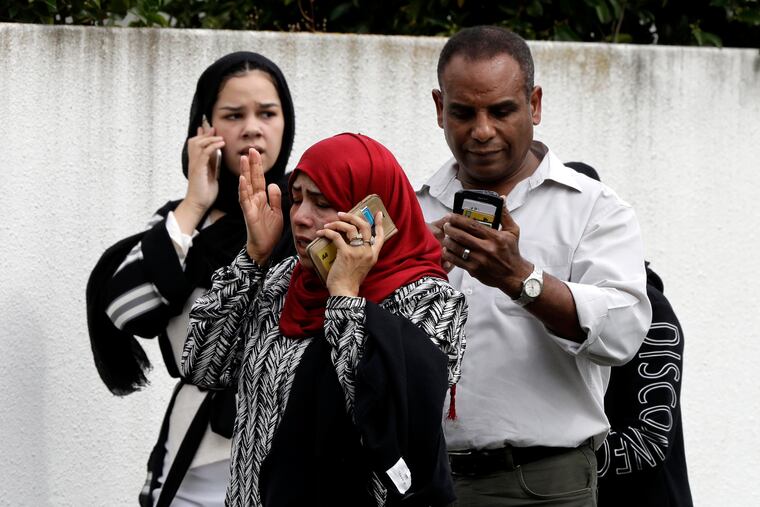 People wait outside a mosque in central Christchurch, New Zealand, on Friday.