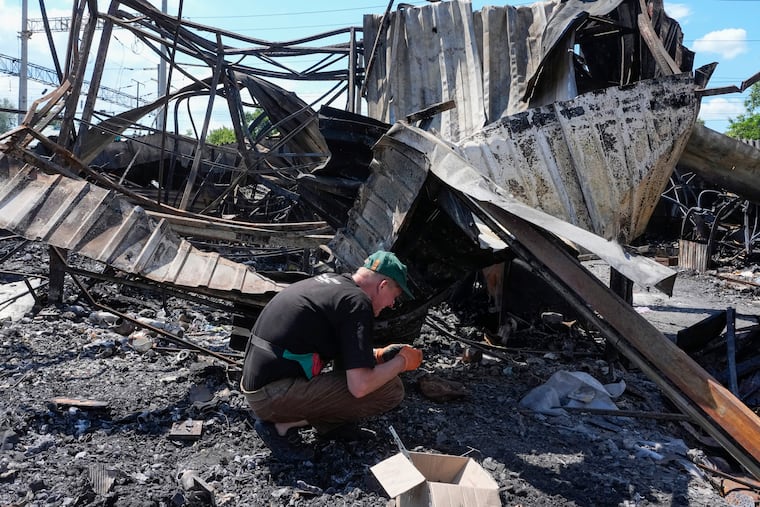 An owner rummages through ashes Wednesday on the site of a ruined city marketplace after a Russian missile attack in Kyiv, Ukraine.