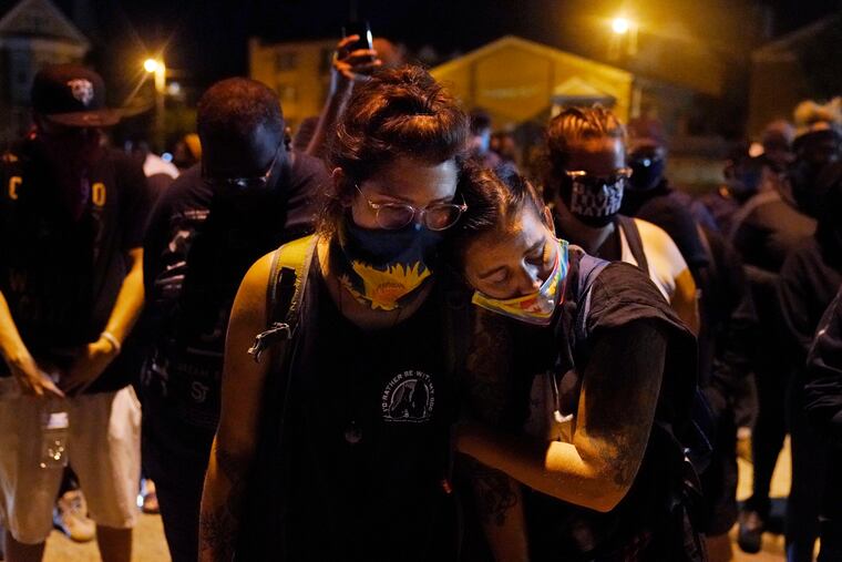 Protesters observe a moment of silence while marching Wednesday night, Aug. 26, 2020, in Kenosha, Wis., near the scene of a fatal shooting Tuesday night. A white, 17-year-old police admirer was arrested Wednesday after two people were shot to death Tuesday during a third straight night of protests in Kenosha over the police shooting of a Black man, Jacob Blake.