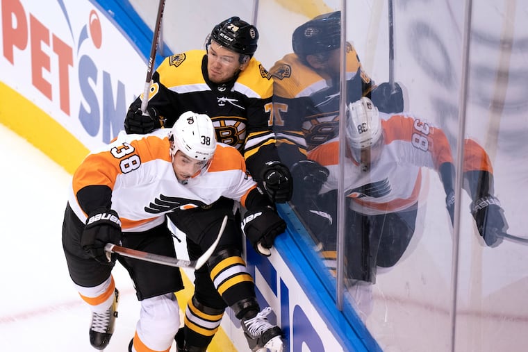 Flyers center Derek Grant and Boston Bruins defenseman Jeremy Lauzon mix it up along the boards during first-period Sunday.
