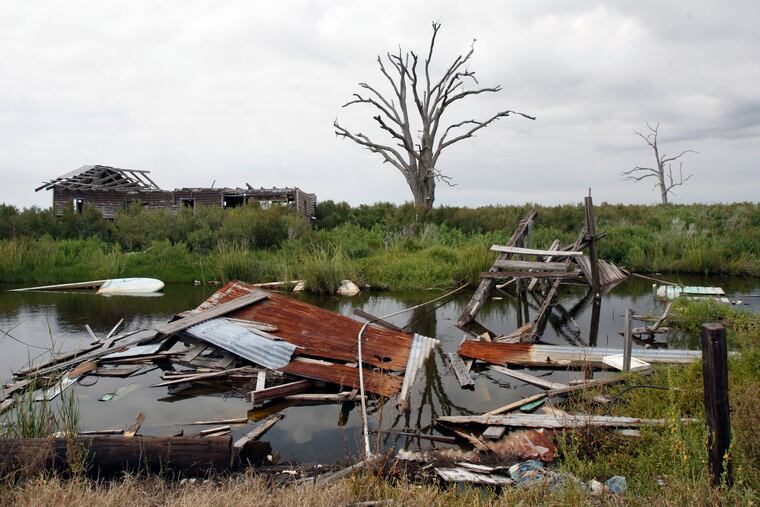 This Sept. 29, 2009 photo shows a dead tree and debris from storms on Isle de Jean Charles, La. Holdouts in the hurricane-damaged Indian village refuse to give in to urges from a tribal chief, scientists and public officials to relocate inland, despite frequent floods and disappearing marshland that brings the Gulf of Mexico closer every year.
