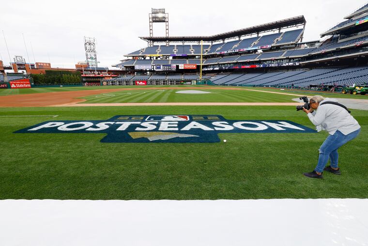 Phillies team photographer Chandra Jones makes a photograph of the MLB postseason logo that the grounds crew had just painted on the playing field at Citizens Bank Park. The 11-year-wait is about to end.