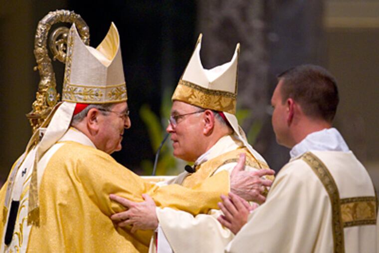 Retiring Cardinal Justin Rigali (left) embraces his successor, Archbishop Charles J. Chaput, at the Cathedral Basilica of SS. Peter and Paul. (Charles Fox / Staff Photographer)