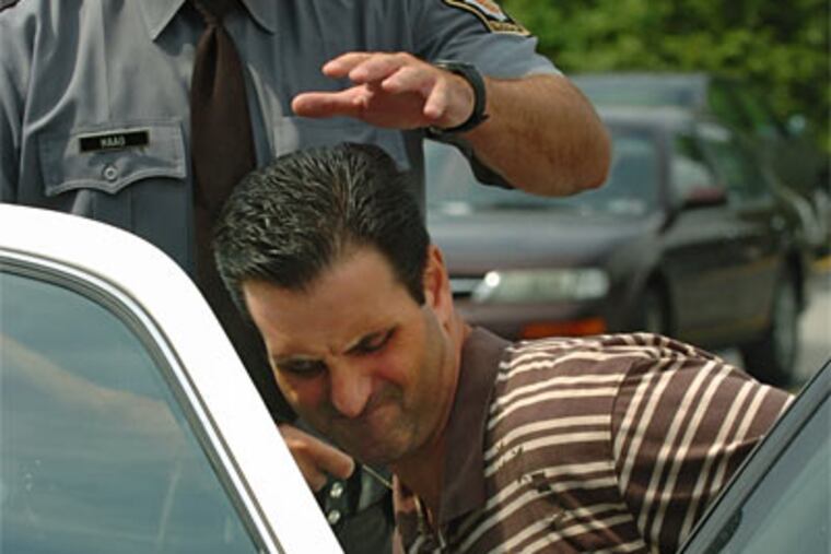 Alleged mob ringleader Louis "Bent Finger Lou" Monacello is led by State Troopers to the District Justice for arraignment in July. (Photo by Clem Murray / Inquirer)