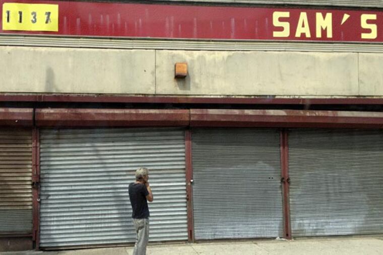 A man stands outside a discount store on Camden's Broadway last fall in a photograph that was included in a group show featuring work by Camden firefighter Gabe Angemi and five other photographers at the Philadelphia Photo Arts Center. (Credit: Gabe Angemi)