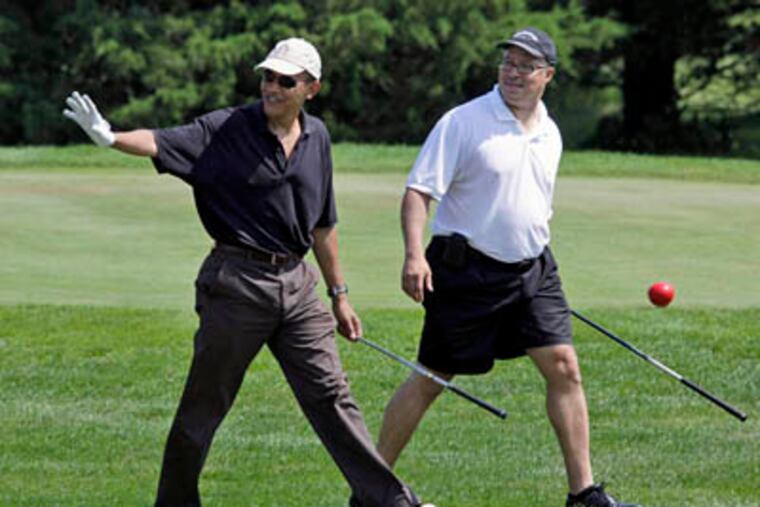 President Barack Obama waves as he walks with Dr. Eric Whitaker as they play golf during his vacation on Martha's Vineyard in Oak Bluffs, Mass., on Monday. (AP Photo / Alex Brandon)