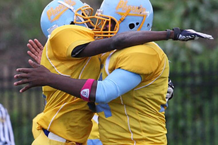 Comm Tech's Devon Brunson (left) celebrates with Herron McBride after he ran an interception in for a touchdown. (Steven M. Falk/Staff Photographer)