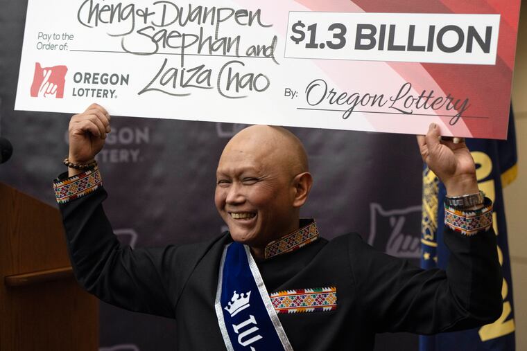Cheng "Charlie" Saephan holds a check above his head after speaking during a news conference where it was revealed that he was one of the winners of the $1.3 billion Powerball jackpot at the Oregon Lottery headquarters on Monday, April 29, 2024, in Salem, Ore.
