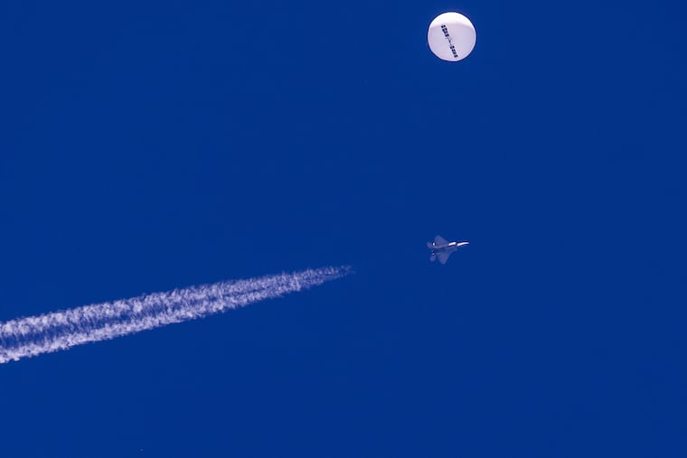 In this photo provided by Chad Fish, a large balloon drifts above the Atlantic Ocean, just off the coast of South Carolina, with a fighter jet and its contrail seen below it, Saturday, Feb. 4, 2023. A missile fired on Feb. 5 by a U.S. F-22 off the Carolina coast ended the days-long flight of what the Biden administration says was a surveillance operation that took the Chinese balloon near U.S. military sites. (Chad Fish via AP)