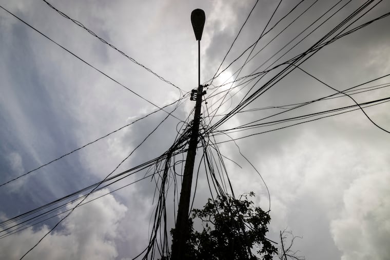 A utility pole with loose cables towers over a home in Loiza, Puerto Rico, in 2022.