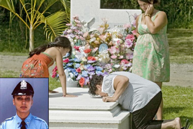 Pat Santiago kisses the grave of her daughter Isabell Nazario as Isabell's daughter Jazmin watches. Jazmin's cousin Briyanna Carrasquillo is at left. The cemetery is located in Mayaguez, Puerto Rico, Ms. Santiago's hometown. (Clem Murray / Staff Photographer)