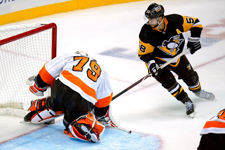 Pittsburgh Penguins defenseman Kris Letang (58) backhands the puck under the pad of Flyers goaltender Carter Hart for the game-winning goal in overtime Thursday.