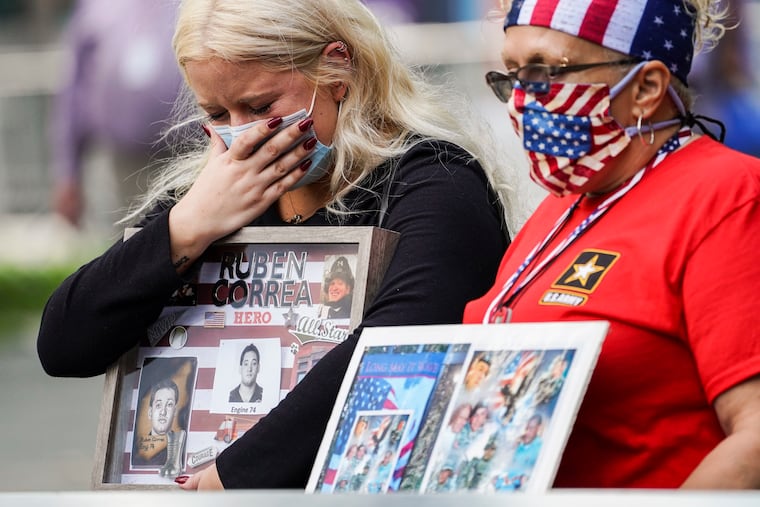 Jo Anne Barbara cries while holding a frame collage of Ruben Correa, a fallen FDNY firefighter, at the National September 11 Memorial and Museum, Friday, Sept. 11, 2020, in New York. Americans will commemorate 9/11 with tributes that have been altered by coronavirus precautions and woven into the presidential campaign.