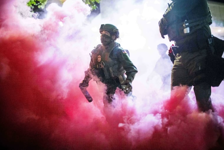 Police and federal officers throw gas canisters to disperse protesters near a U.S. Immigration and Customs Enforcement facility in Portland, Ore., in October.