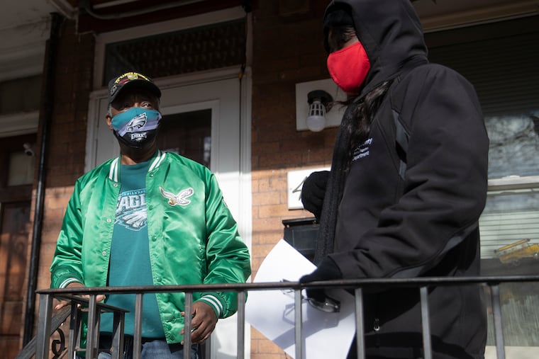 Resident Karl Beverly comes out of his home in Camden, N.J. and speaks with Kyisha Lingo of the Camden County Department of Health on Tuesday, Dec. 08, 2020. Camden has had a recent surge of new COVID-19 cases. A group of health education specialist, along with the police, have been going around the neighborhood to speak with residents in the Waterfront South neighborhood in order to combat the spread of the coronavirus.