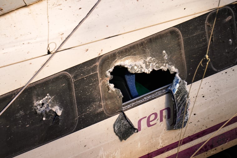 Broken windows of a crashed train are photographed at the site of a collision in Adamuz, southern Spain, on Monday, Jan. 19.
