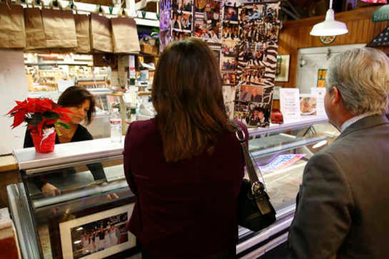 Antoinette Finocchio puts up photos at Harry's stand in the Reading Terminal Market. A funeral luncheon was held Monday in a re- served section at the Market; Ochs was a fixture in the business for 62 years.