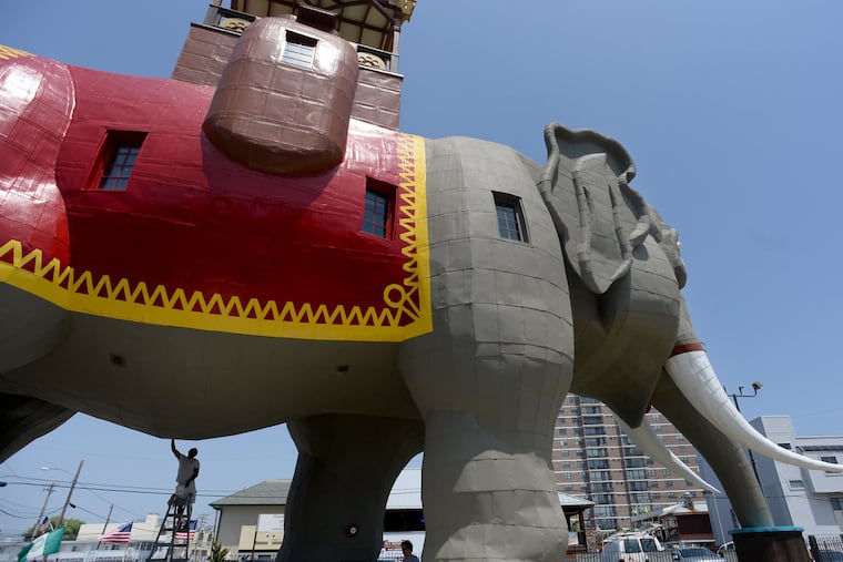 Painting contractor Jose Luna (bottom, left) is under the belly of the beast as he touches up paint on the six-story Lucy the Elephant in Margate on July 14, 2016, getting her ready for her 135th birthday celebration.
