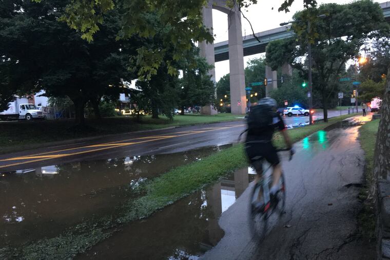 Cyclist rides along Kelly Drive early Tuesday morning after floodwaters receded along the Schuylkill.