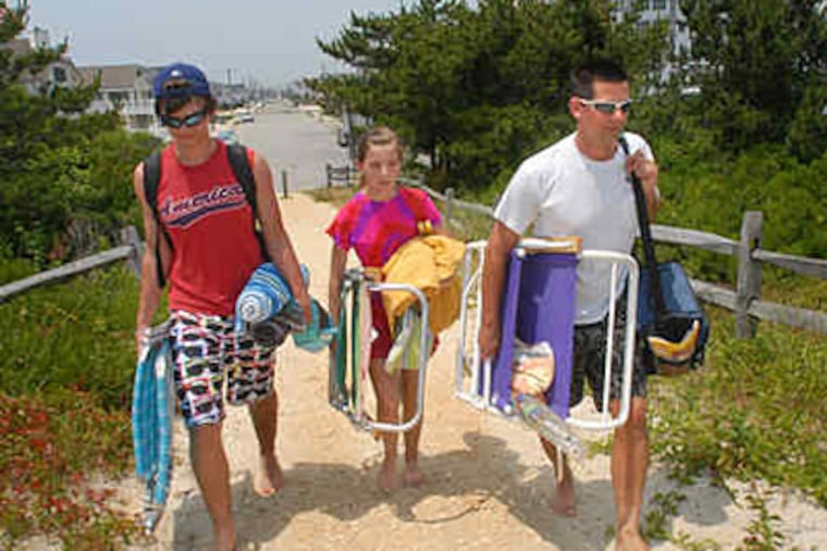 Jacob (left) and Michaela Hill and their father, Stewart, walk from 75th Street to the ocean in Avalon. Area heat records could fall today and tomorrow. (April Saul / Staff)