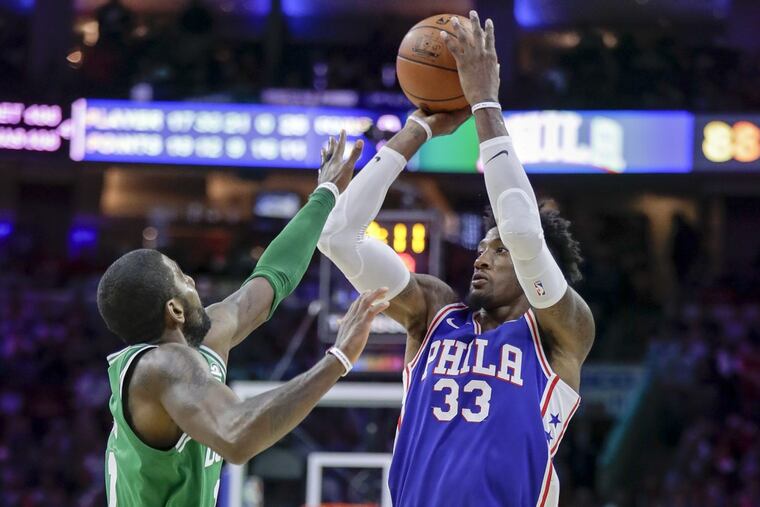 Sixers forward Robert Covington shoots over Boston Celtics guard Kyrie Irving during the game between the teams at the Wells Fargo Center in October.