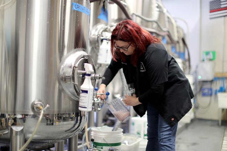 Lori White, co-owner of Zed's Beer, samples of a beer from one of their stainless steel tanks at the brewery..
