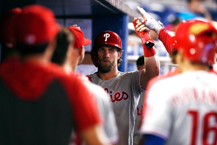 Bryce Harper fist-bumps his teammates after scoring on Sunday.