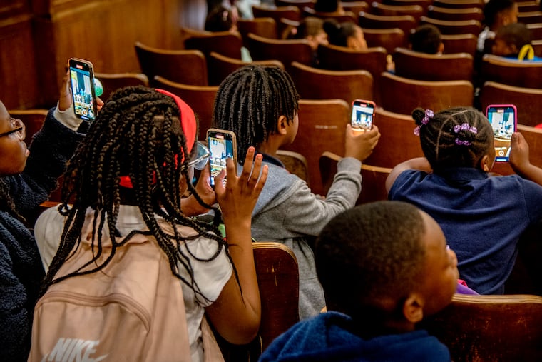 Students at the J.S. Jenks Academy in Chestnut Hill, record video as they attend presentations in the auditorium, celebrating Reading Promise Week and family literacy.