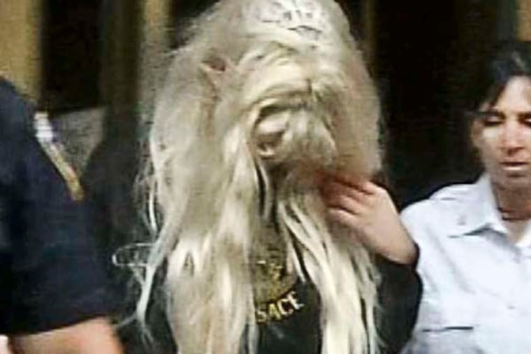 In an image made from video, actress Amanda Bynes, center, wearing sweats and a blonde wig, is escorted after a Manhattan criminal court appearance on Friday May 24, 2013 in New York. Bynes was arrested Thursday evening and charged with reckless endangerment after police say she heaved a marijuana bong out of out of her Manhattan apartment building. (AP Photo/APTN)
