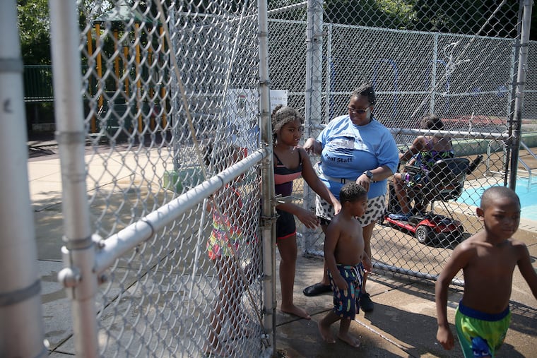 Pool maintenance attendant Jeneen Helms, rear, allows kids back into the pool at the Baker Playground pool in West Philadelphia on Saturday, July 20, 2019. Helms was working when seven people were shot at the playground during a cookout July 13.