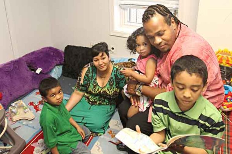 A program nicknamed "Baby College" has come to Camden through the Promise Neighborhood Family Success Center. It aims to help parents do a better job -- and ease the child developmental effect of what's now being recognized as a public health issue: poverty. In the the "Book NooK"/computer center, Daghee Shakes, 7, right, reads a book as L-R: his brother Rajeev, his mother Sherri Shakes, sister Maexing, and father Darnell Shakes look on. ( CHARLES FOX / Staff Photographer )