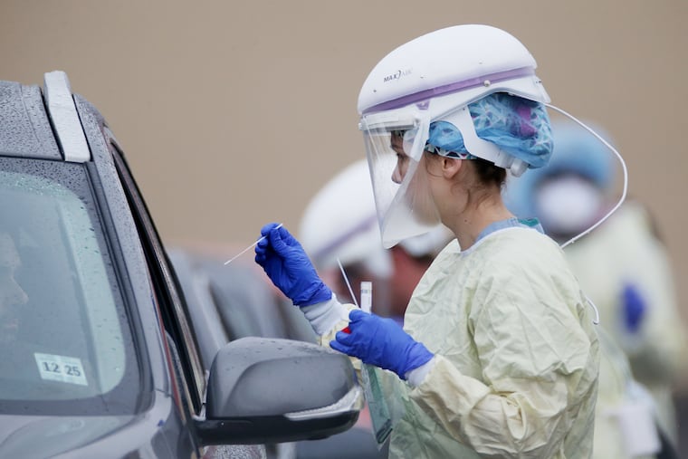 A medical worker collects samples from individuals who signed up for drive-through testing for the coronavirus at a Penn Medicine site in West Philadelphia on Tuesday.