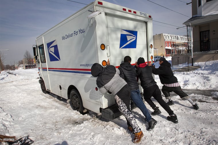 Young men from the Mantua section of Philadelphia attempt to help a stranded U.S Postal truck stuck in the snow and ice along Union St. at Fairmount on Monday afternoon.