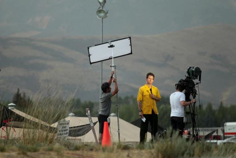 Paul Beban, center, Denver Correspondent for Al Jazeera America, reports from the main fire camp for the Beaver Creek Fire in Hailey, Idaho on Tuesday Aug. 20, 2013. The Qatar-based Al-Jazeera Media Network launched its U.S. outlet only eight months after announcing the new venture, which replaced Al Gore's Current TV in more than 45 million TV homes Tuesday. (AP Photo/The Times-News, Ashley Smith)