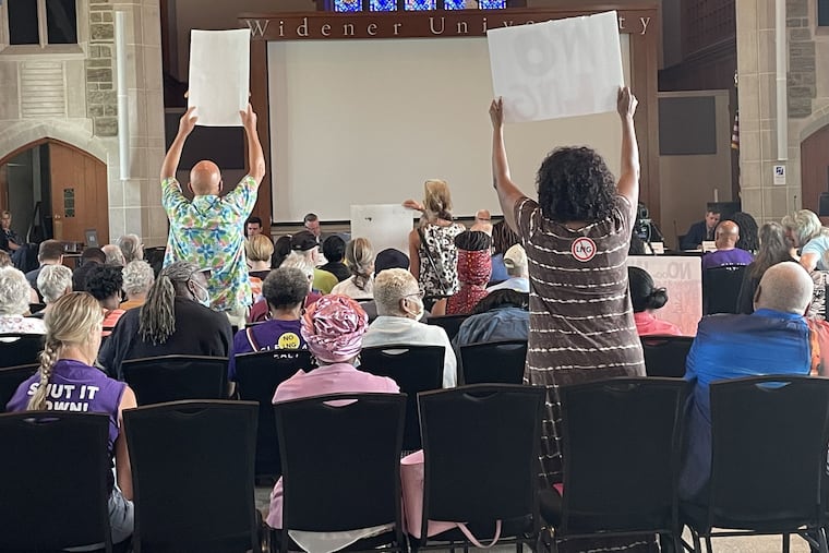 Protesters hoist signs during testimony at a public hearing at Widener University, in Chester, in August on a proposed Liquefied Natural Gas facility.