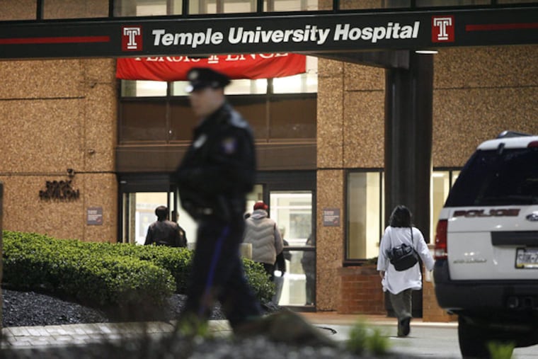 A Temple police officer walks near front of Temple University Hospital as employees start to arrive (right) in the early morning.