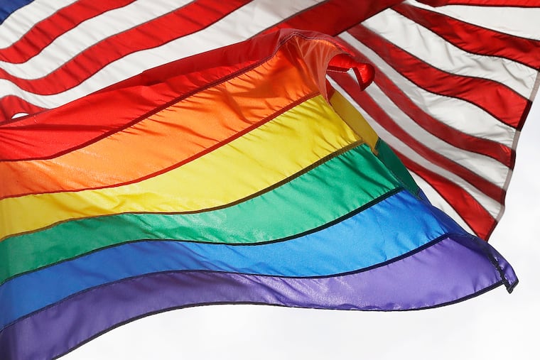 FILE - An LGBTQ+ pride flag flies beneath a U.S. flag at the Stonewall National Monument in New York, on Oct. 11, 2017. (AP Photo/Mark Lennihan, File)