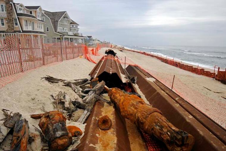 The remains of a ship rest on sections of sea wall being installed on Normandy Beach in Brick, NJ November 13, 2014.( TOM GRALISH / Staff Photographer )